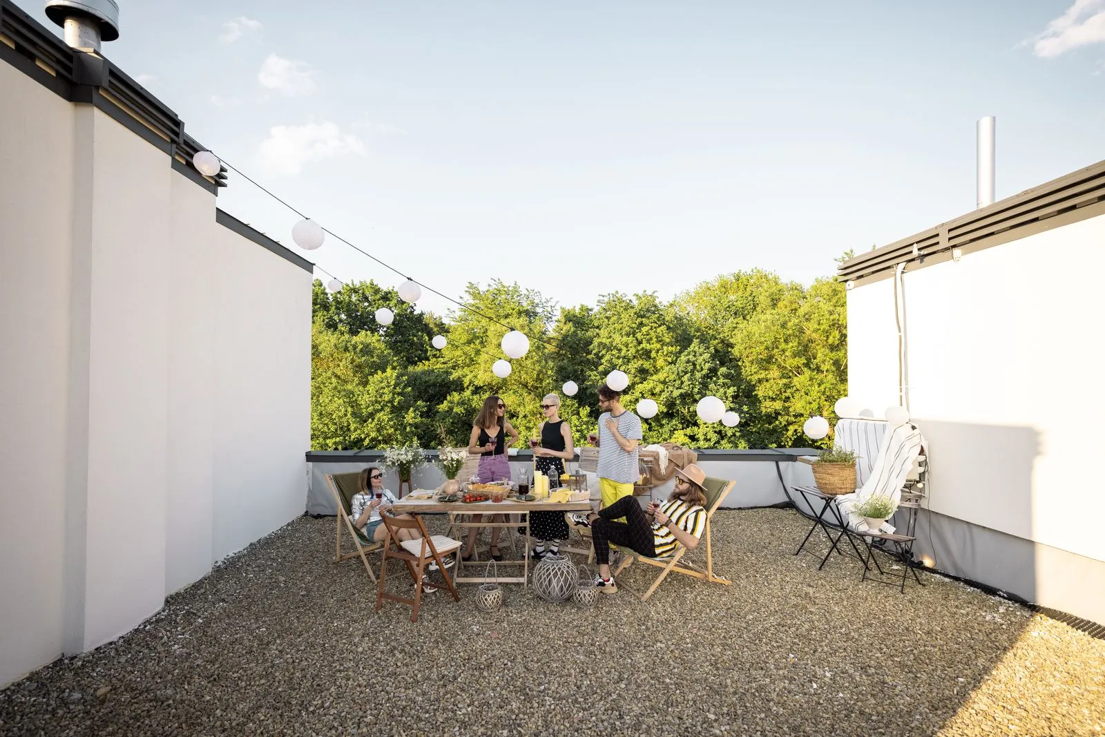 Neighbors gathered around a table on an apartment rooftop terrace at sunset